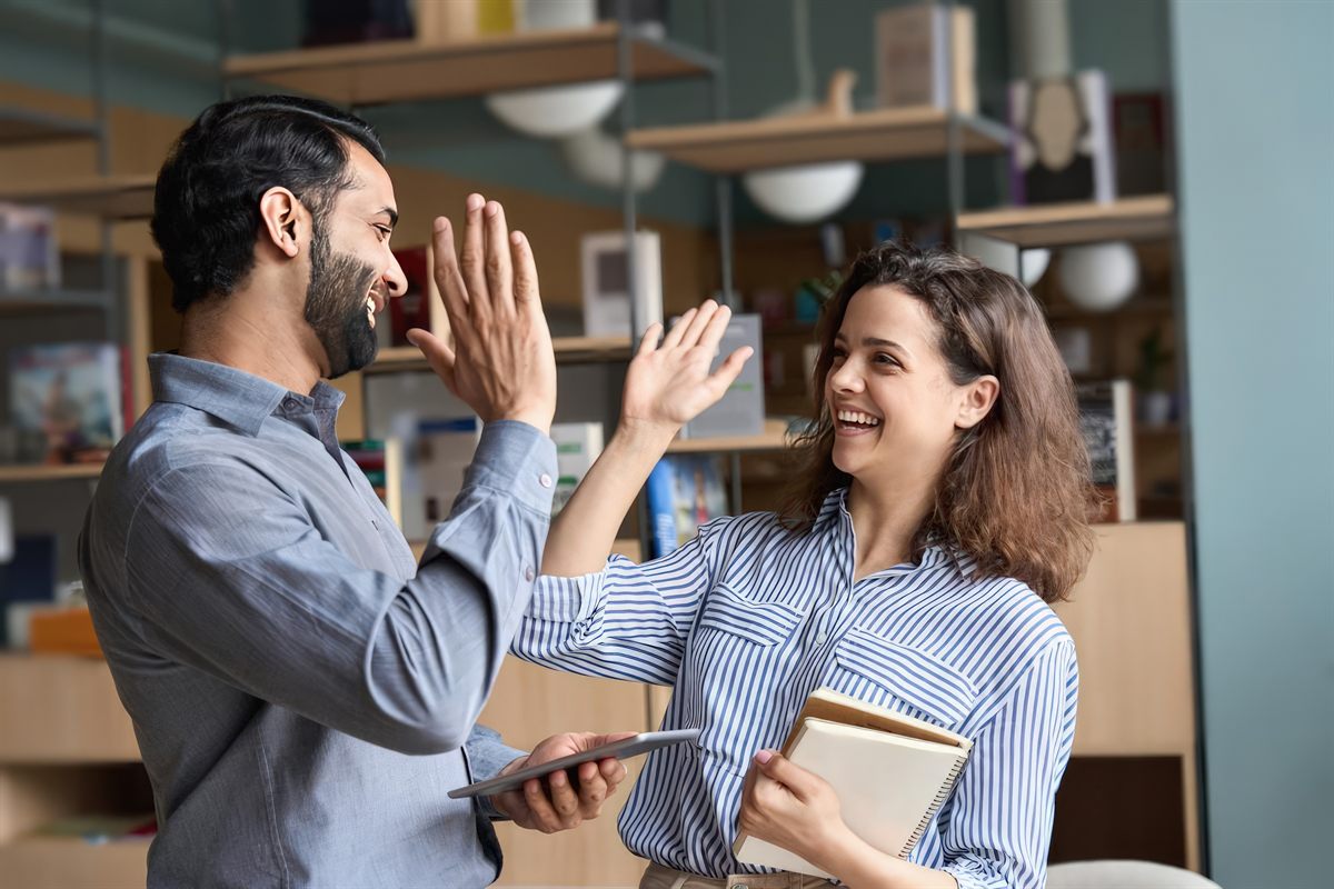 Zwei Personen geben sich im Büro ein High-Five